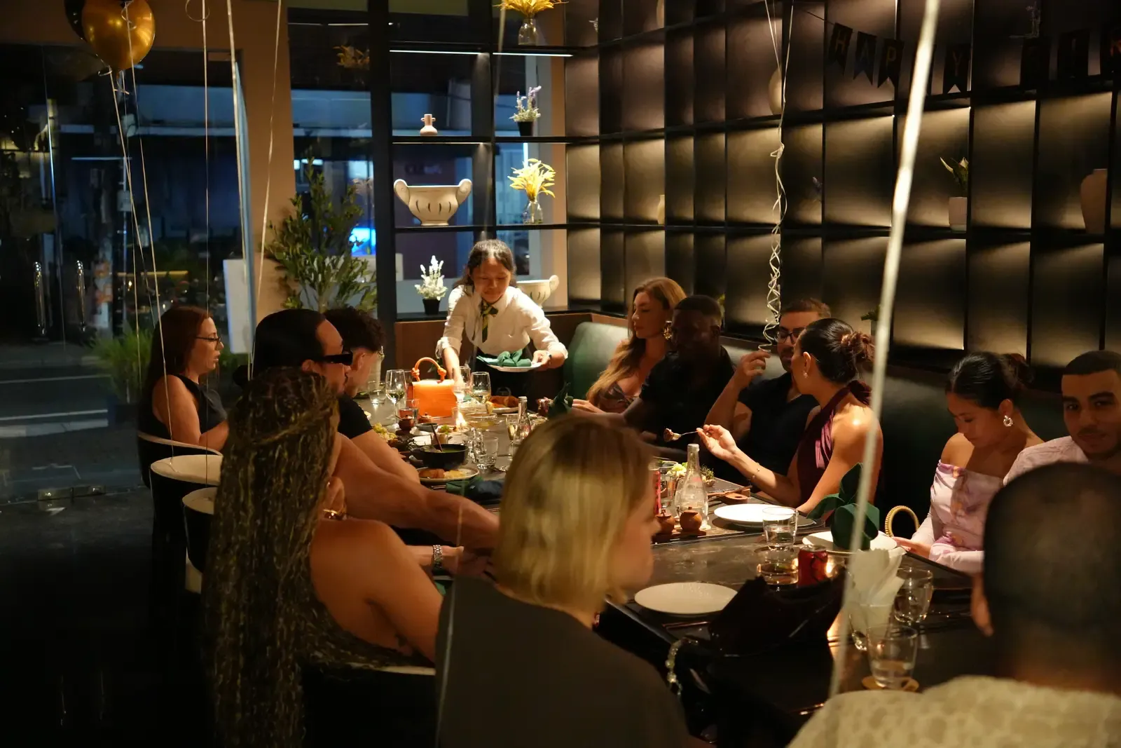Friends celebrating a birthday dinner around a long table at Maison Almaz, Canggu