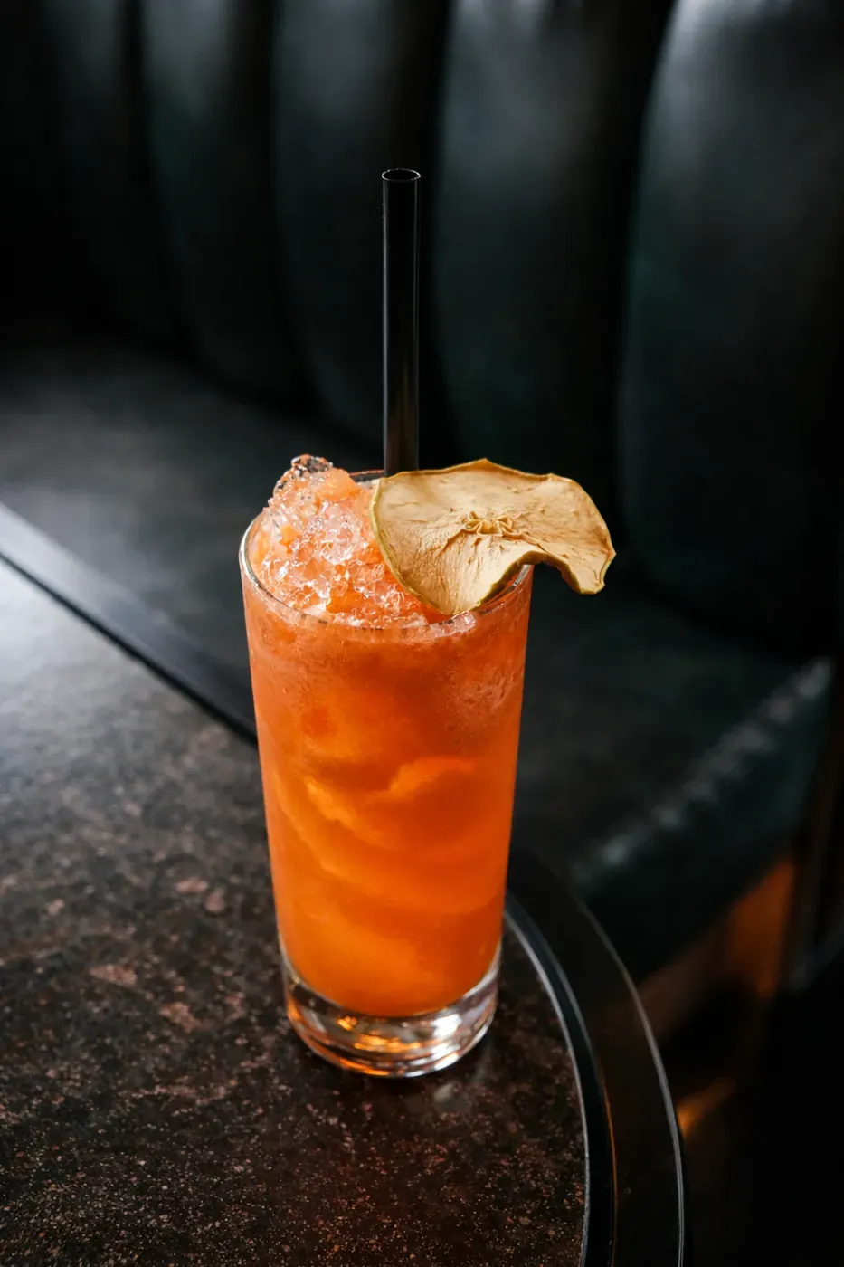 Tall citrus cocktail with a dried ginger garnish