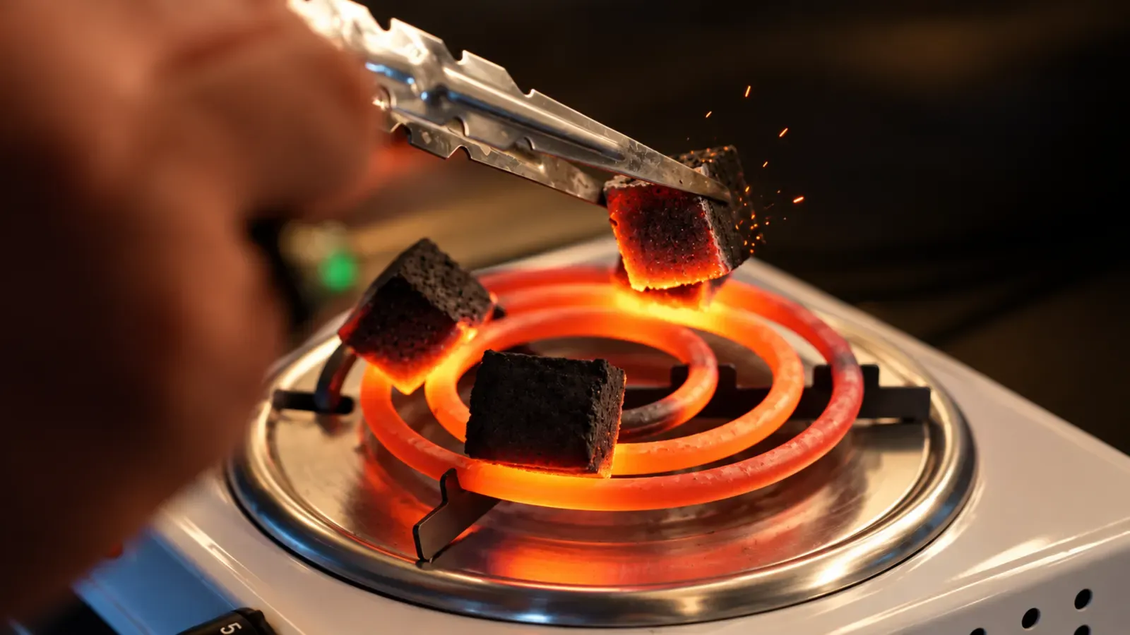 Tongs lifting a red-hot coconut coal for a shisha at Maison Almaz, Canggu